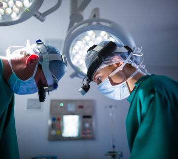Surgeons wearing surgical loupes while performing operation 360x320